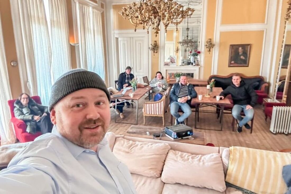 Deltakere samlet i en lokale med bord og lysekroner